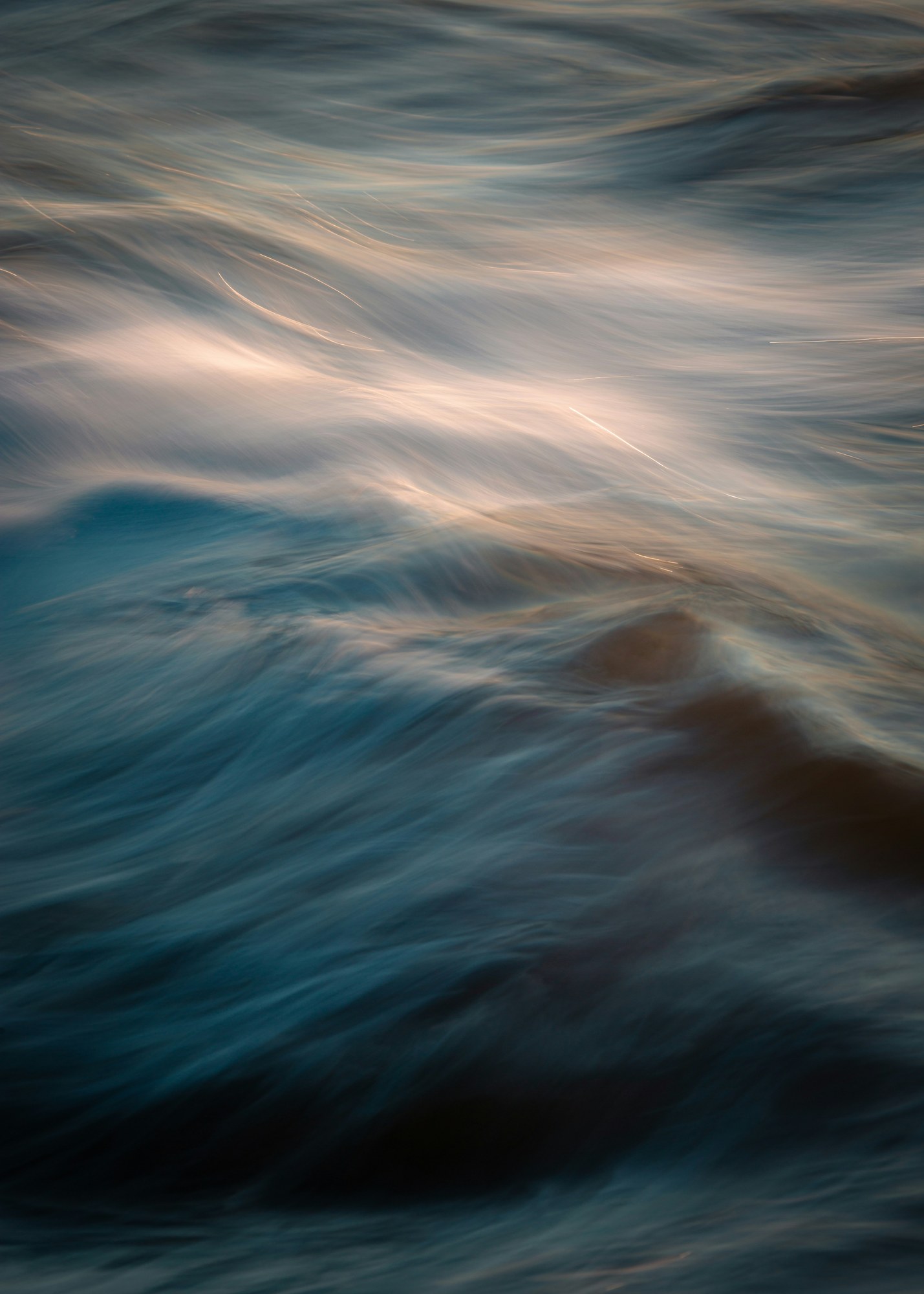 Soft streaks of light and colour across moving ocean water.